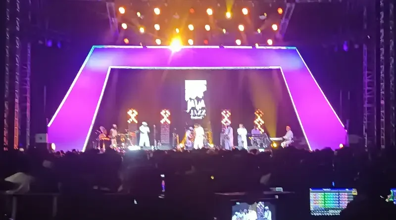 Gitar elektrik klasik di atas panggung dengan pencahayaan warna-warni nuansa disko dan funk.