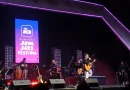 Ilustrasi simbolik panggung festival jazz dengan sorotan lampu pada instrumen gitar