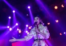 Simbol festival musik panggung megah dengan tata lampu sorot di malam hari.