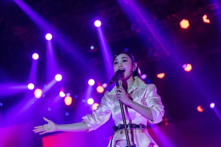 Simbol festival musik panggung megah dengan tata lampu sorot di malam hari.