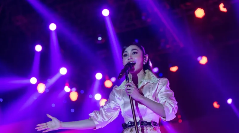 Simbol festival musik panggung megah dengan tata lampu sorot di malam hari.