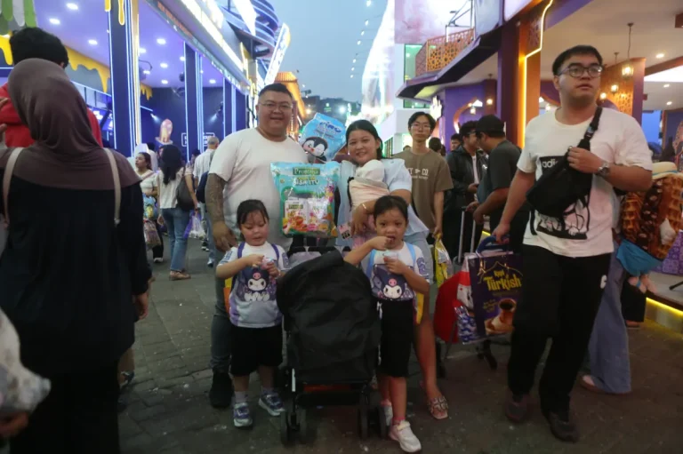 Suasana pameran festival malam hari yang meriah dengan lampu warna-warni dan stan pengunjung.