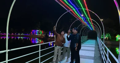 Pemandangan instalasi lampu warna-warni di area danau pada malam hari.