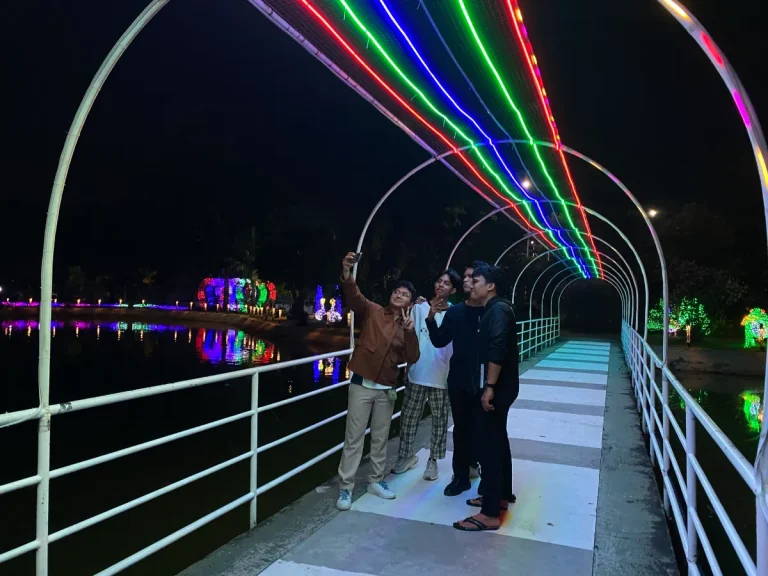 Pemandangan instalasi lampu warna-warni di area danau pada malam hari.