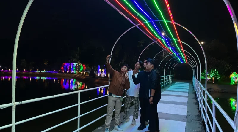 Pemandangan instalasi lampu warna-warni di area danau pada malam hari.