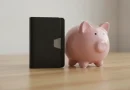 Ilustrasi dompet digital tertutup dan celengan babi di atas meja kayu sebagai simbol cara menghindari pengeluaran impulsif.