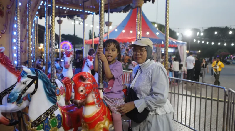 Wahana komidi putar warna-warni berputar indah di sebuah taman bermain malam hari