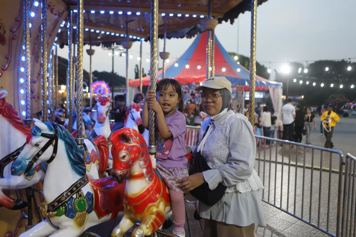 Wahana komidi putar warna-warni berputar indah di sebuah taman bermain malam hari