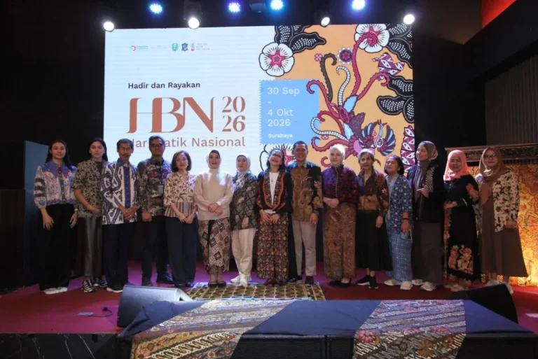 Perahu tradisional dihias motif batik Jawa Timur berlayar di sungai, merepresentasikan perpaduan budaya dan modernitas.