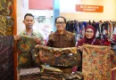 Lembaran kain batik tradisional dengan motif Jawa Timur tertata di atas meja kayu artistik