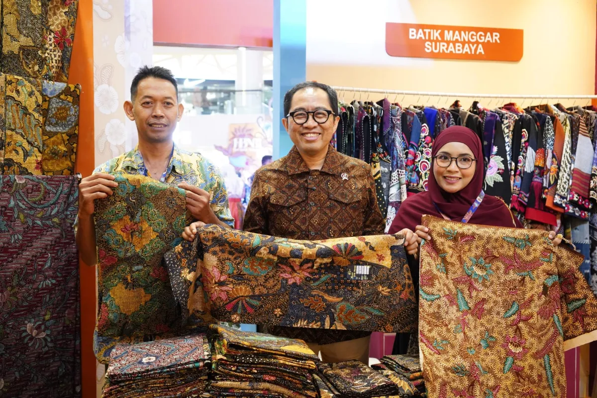 Lembaran kain batik tradisional dengan motif Jawa Timur tertata di atas meja kayu artistik