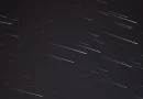 Ilustrasi teleskop kuno dan peta rasi bintang di bawah langit malam penuh bintang